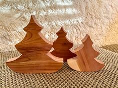 three wooden christmas trees sitting on top of a table next to a white wall and carpet