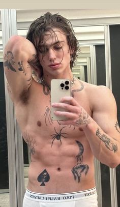 a shirtless man taking a selfie in front of a mirror with his cell phone