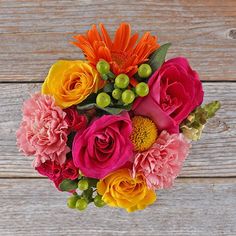 a bouquet of colorful flowers sitting on top of a wooden table