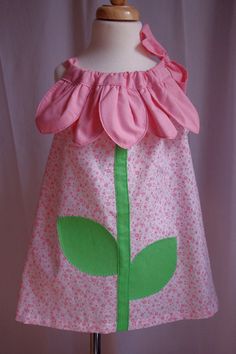 "Adorable little dress that is perfect for Spring and Summer wear. Perfect for the birthday girl. Applique flower stem with leaves that have hand-embroidered edge details. Neckline has five petals that make your little girl feel like her favorite flower. Wide drawstring neckline ties at one shoulder, so it is easily adjustable. Hemmed by hand. Made of cool and comfy 100% cotton.  Size 4. Length, measured in back from top edge to hem approx. 19 1/2\" (does not include ties/straps). Width from armpit to armpit is approx. 15 1/2\" across. Fabric has a white background with tiny pink hearts and flower print.  Stem applique is green and petals are bubblegum pink. What little girl would not feel so special wearing this fun dress. Handmade in the USA. Can be washed in the machine, cold water, gen Easter Dress Toddler, Flower Petal Dress, Sundress White, Petal Dress, Baby Clothes Patterns Sewing, Sewing Kids Clothes, Kids Frocks Design