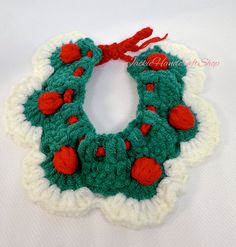 a crocheted christmas wreath ornament with red and green pom - poms