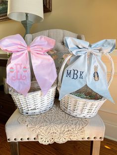 two white baskets with pink and blue bows are sitting on a chair next to a lamp