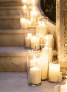 candles are lined up on the steps in front of a clock and stairs with gold lettering