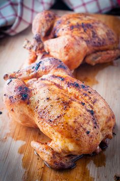 two whole chickens sitting on top of a wooden cutting board