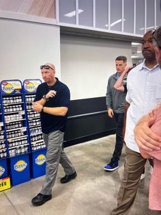 two men are talking to each other in front of some blue and white boxes with advertisements on them