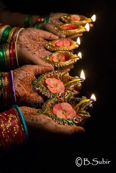 two hands with hendi holding lit candles in front of the words happy diwali