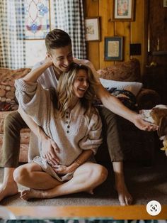 a man sitting on the floor next to a woman who is holding her head and smiling