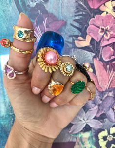 a woman's hand holding several rings with different colors and designs on them, including sunflowers