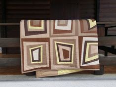 a brown and yellow quilt sitting on top of a wooden bench