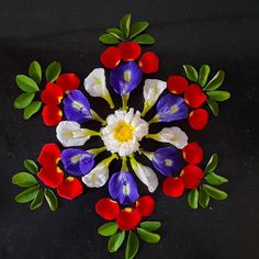 an arrangement of flowers arranged in the shape of a snowflake on a black surface