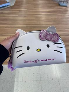 a hello kitty purse with a pink bow on it's head is being held by a person