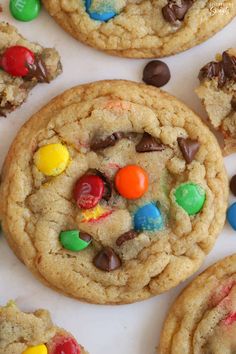 chocolate chip cookies with m & m and m's in the middle on a white surface