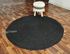 a black rug sitting on top of a hard wood floor next to a white stool