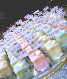 many different types of marshmallows are on a tray with small signs that say eat me and eat me