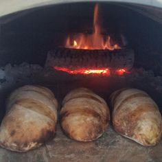 four loaves of bread sitting in front of an open fire