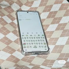 a cell phone sitting on top of a checkered tablecloth covered table with an embossed keyboard