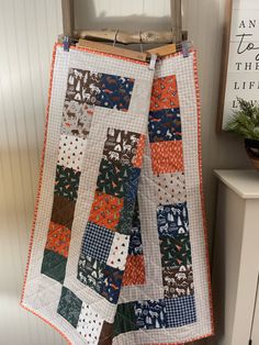 a quilt hanging on a clothes line next to a potted plant in a room