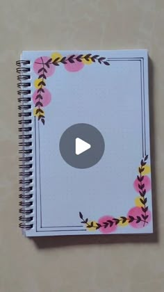 an open notebook with a video playing on the page in front of it and flowers around the corner