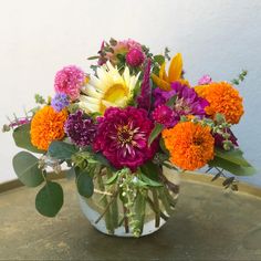 a vase filled with lots of different colored flowers