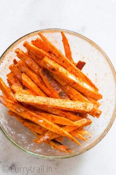 a glass bowl filled with french fries on top of a white countertop next to a knife