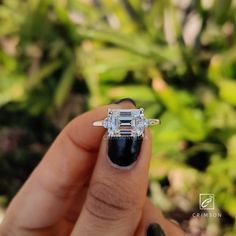 a person holding up a ring with an emerald stone in it's middle finger