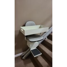 an office chair sitting on top of a stair case next to a wall and carpeted floor