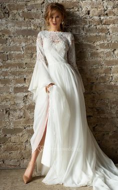 a woman in a white dress standing next to a brick wall with her legs crossed