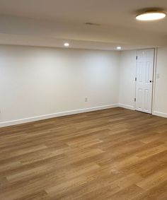 an empty room with hard wood floors and white walls