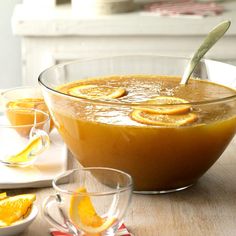 a bowl filled with orange slices on top of a wooden table next to other bowls