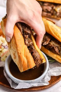 a person is grabbing a sandwich from a plate with other food on the table behind them