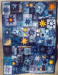 a quilt hanging on the side of a wooden fence with stars and moon in it