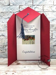 a graduation card in a red envelope with a tasseled cap on the top