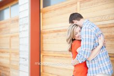 a man and woman hugging in front of a wooden wall