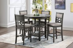 a dining room table and chairs with a rug on the floor in front of it