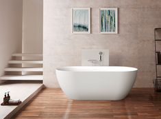 a white bath tub sitting on top of a hard wood floor next to a stair case