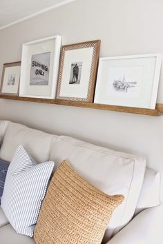 three framed pictures hang on the wall above a white couch with blue and white pillows