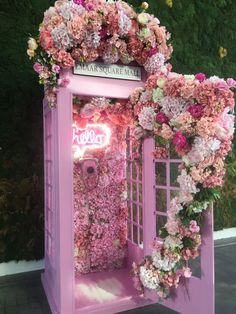 a pink phone booth decorated with flowers