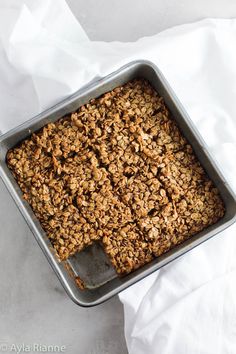 a pan filled with granola sitting on top of a white cloth covered tablecloth