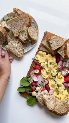 two plates filled with food on top of a white table next to another plate full of bread