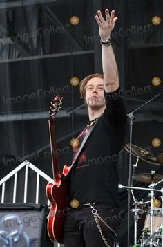 a man holding his hand up in the air while standing next to a guitar on stage