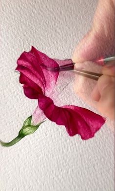 someone is painting a flower with watercolors on paper