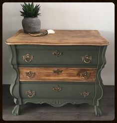 a green dresser with drawers and a potted plant on top