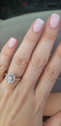 a woman's hand with a pink manicure and diamond ring on her finger