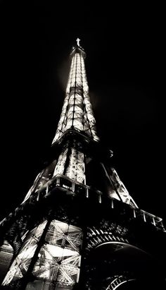 the eiffel tower lit up at night in black and white with its lights on