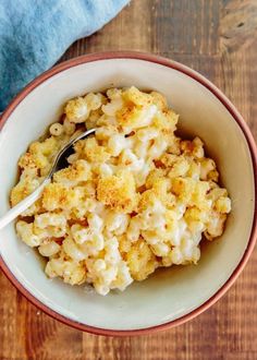 a bowl filled with macaroni and cheese on top of a wooden table