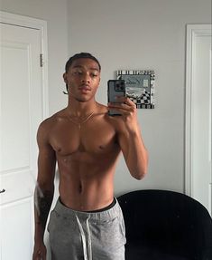 a shirtless man taking a selfie in front of a mirror with his cell phone