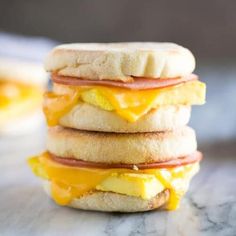 a stack of breakfast sandwiches sitting on top of a marble countertop with eggs, ham and cheese