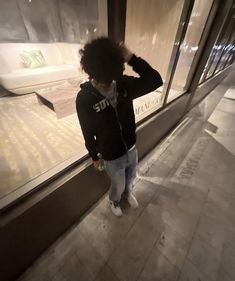 a person standing in front of a store window with their hand on his head and looking at the floor