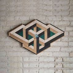 a wooden wall hanging on the side of a brick building with an abstract design made out of wood