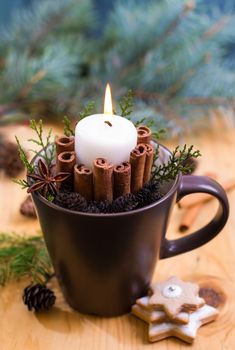 a cup filled with cinnamons and a lit candle on top of a wooden table